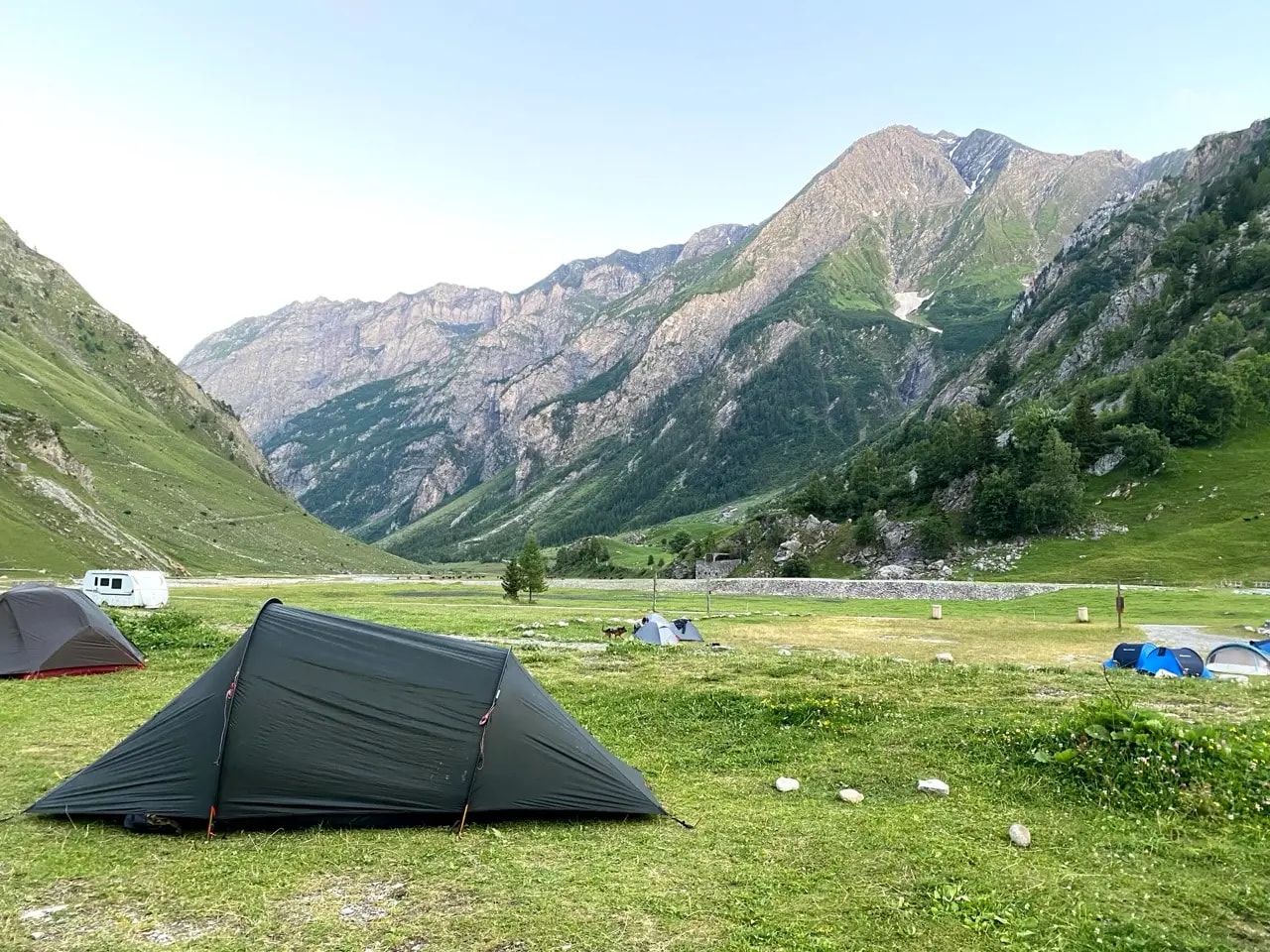 Tents pitched on a grassy campsite in Les Chapieux with mountains in the background Tents pitched on a grassy campsite in Les Chapieux with mountains in the background