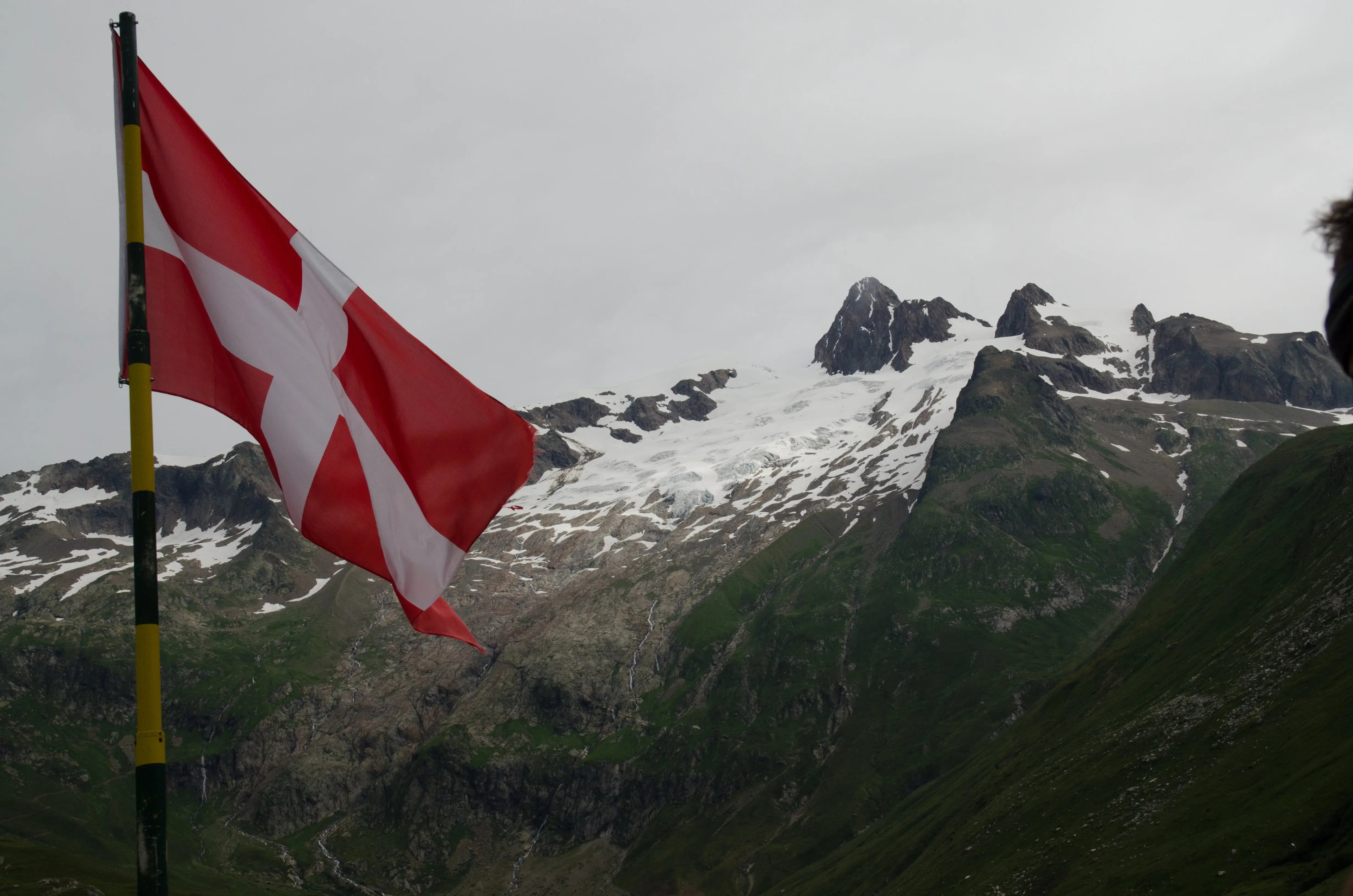 The Swiss regional flag flying against an alpine mountain backdrop on the TMB The Swiss regional flag flying against an alpine mountain backdrop on the TMB